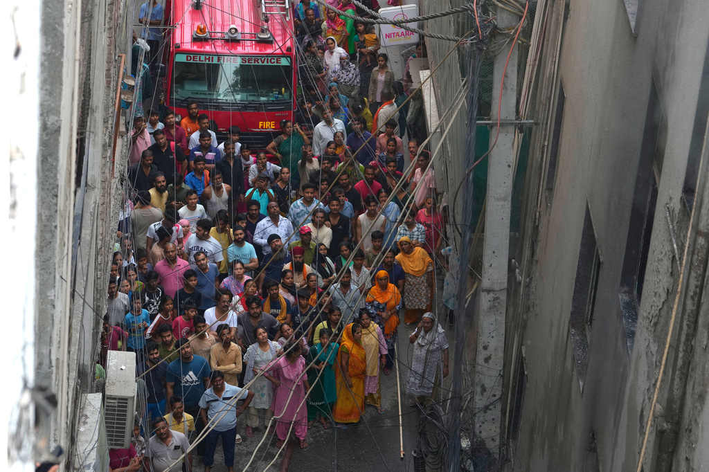Locals and bystanders watch a hotel fire as firefighters work to douse the flames in New Delhi, India, Wednesday, June 3, 2026. (AP Photo/Manish Swarup)