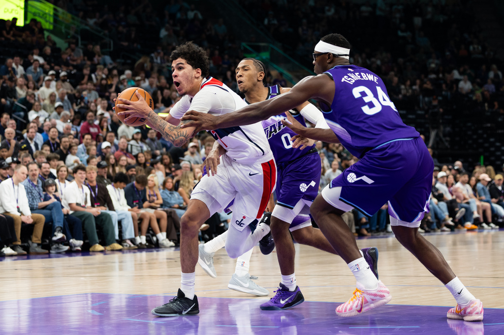 Utah Jazz forward Oscar Tshiebwe (34) and Utah Jazz forward Kennedy Chandler (0) defend Washington Wizards forward Will Riley, left, during the first half of an NBA basketball game, Wednesday, March 25, 2026, in Salt Lake City. (AP Photo/Anna Fuder)
