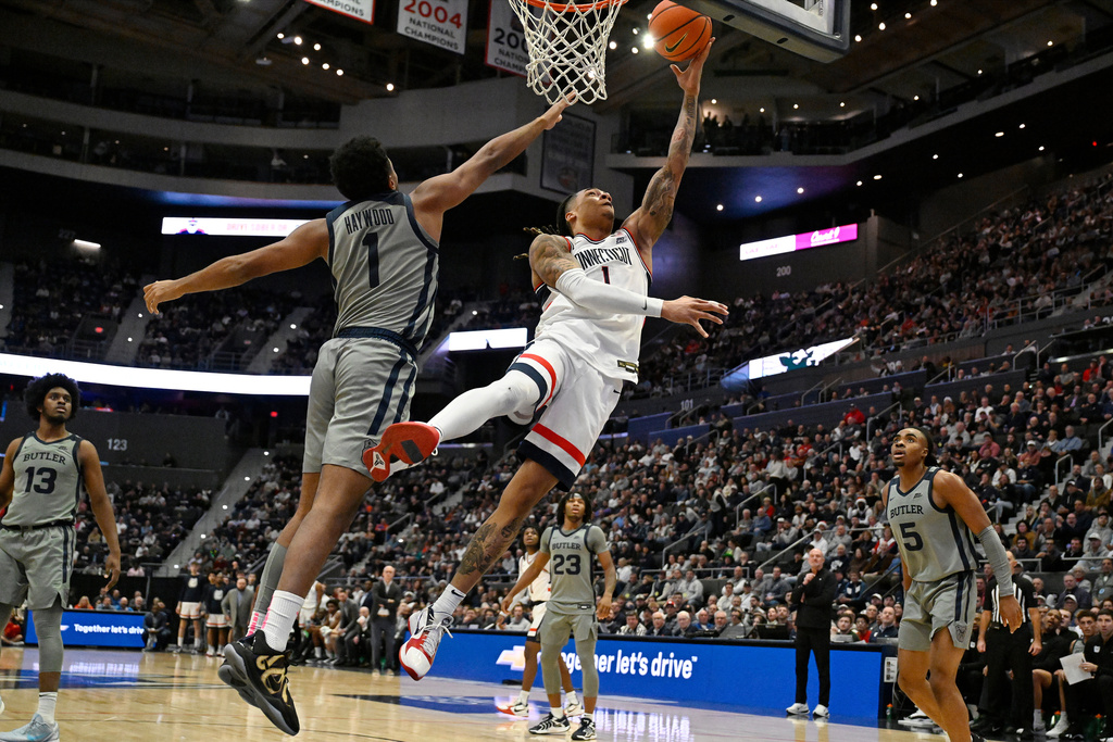 UConn guard Solo Ball (1) shoots as Butler guard Evan Haywood (1) defends in the first half of an NCAA college basketball game, Tuesday, Dec. 16, 2025, in Hartford, Conn. (AP Photo/Jessica Hill)