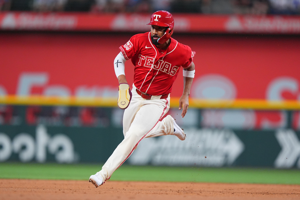 Texas Rangers' Ezequiel Duran runs to third base on way to scoring on a throwing error by Kansas City Royals second baseman Nick Loftin during the first inning of a baseball game, Friday, May 29, 2026, in Arlington, Texas. (AP Photo/LM Otero)
