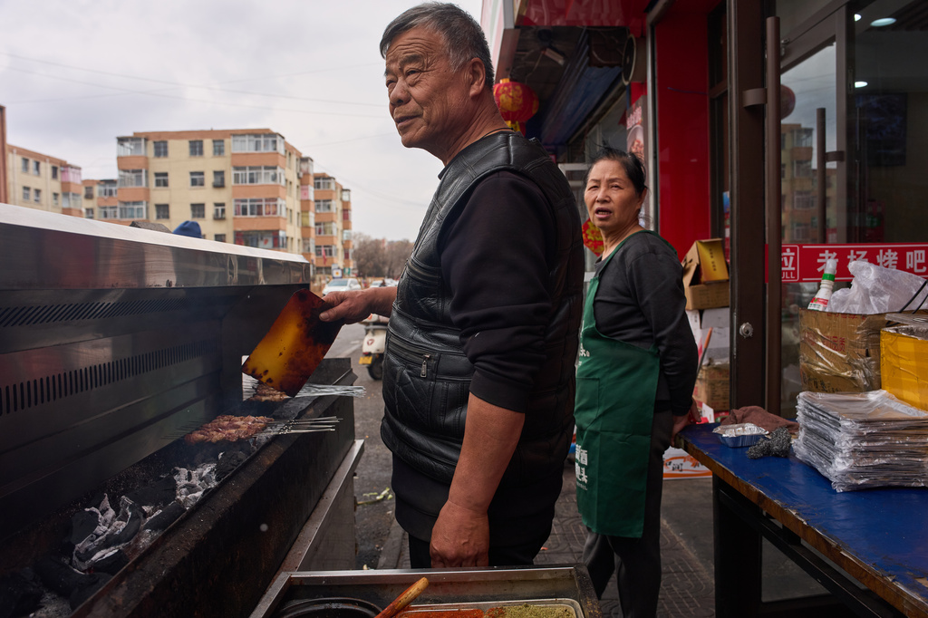 Retired miner Yang Haiming prepares skewers of barbecued meat at a restaurant in Datong, China, Friday, March 13, 2026. (AP Photo/Ng Han Guan)