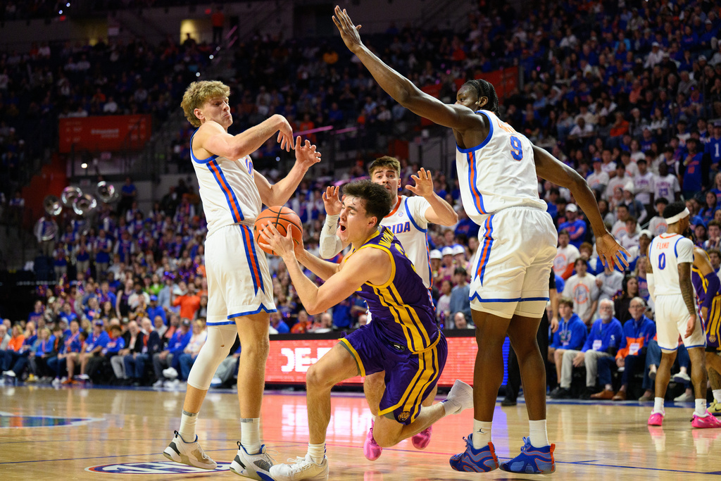 LSU guard Max Mackinnon (3) drives on Florida center Rueben Chinyelu (9) and forward Thomas Haugh (10) during the first half of an NCAA college basketball game, Tuesday, Jan. 20, 2026, in Gainesville, Fla. (AP Photo/Noah Lantor)