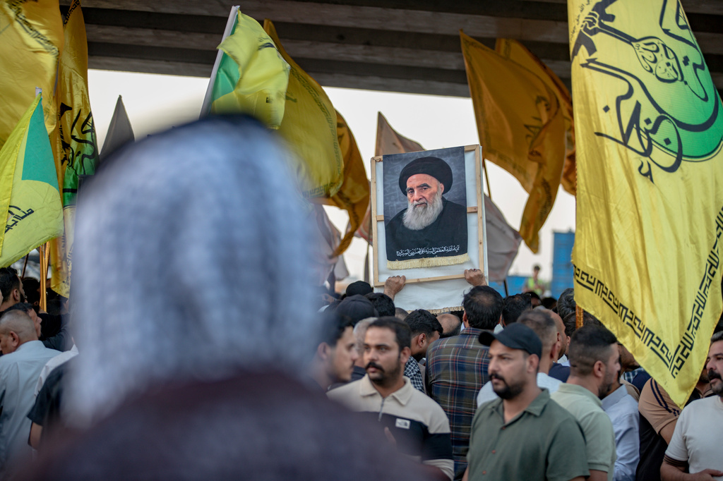A demonstrator holds a portrait of Iraq's top Shiite cleric, Grand Ayatollah Ali al-Sistani, during a protest against the suspension of flights between Iraq and Iran outside Najaf International Airport in Najaf, Iraq, Monday, Sept. 28, 2026. (AP Photo/Anmar Khalil)