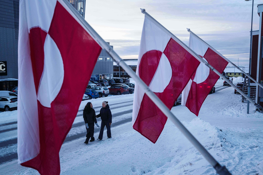 FILE - Women walk on a street in front of national flags in Nuuk, Greenland, Jan. 14, 2026. (AP Photo/Evgeniy Maloletka, File)