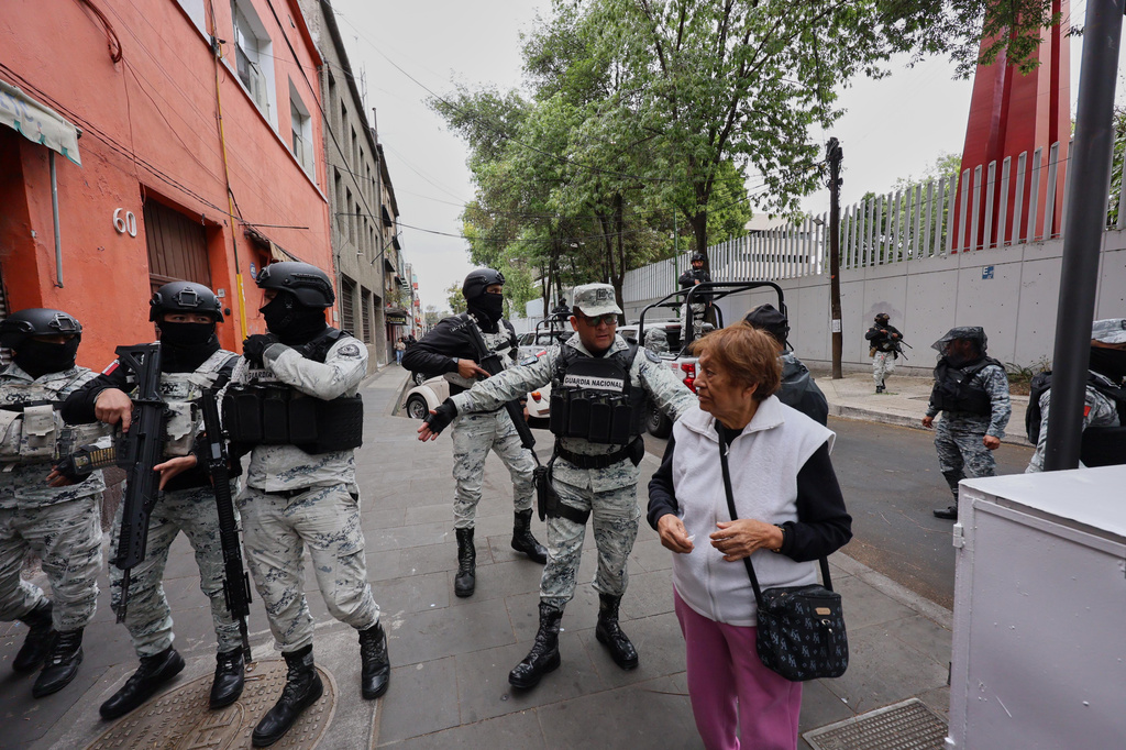 National Guards remove a pedestrian around the General Prosecutor's headquarters in Mexico City, Sunday, Feb. 22, 2026, after the death of the leader of the Jalisco New Generation Cartel, Nemesio Rubén Oseguera Cervantes, known as "El Mencho." (AP Photo/Ginette Riquelme)