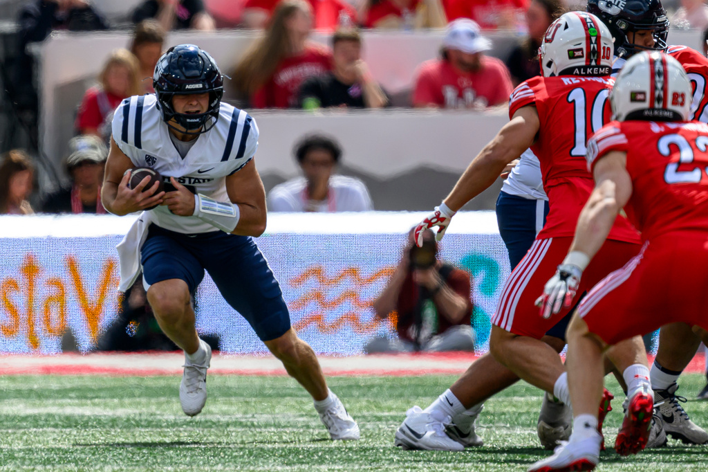 Utah State wide receiver Rex Haynes, left, scrambles for a first down during the first half of an NCAA college football game against Utah, Saturday, Sept. 19, 2026, in Salt Lake City. (AP Photo/Tyler Tate)