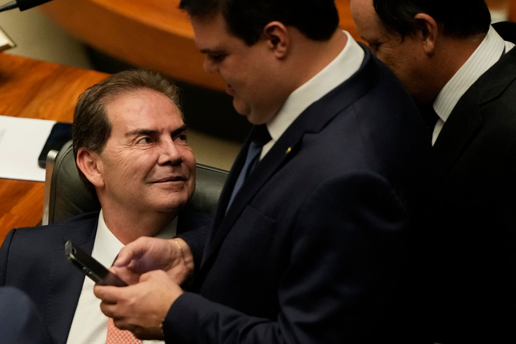 Deputy Paulinho da Forca chats with other congressmen during a session to consider a bill to alter the sentencing guidelines for crimes including leading a coup d'état, for which former President Jair Bolsonaro was sentenced, in Brasilia, Brazil, Tuesday, Dec. 9, 2025. (AP Photo/Eraldo Peres)
