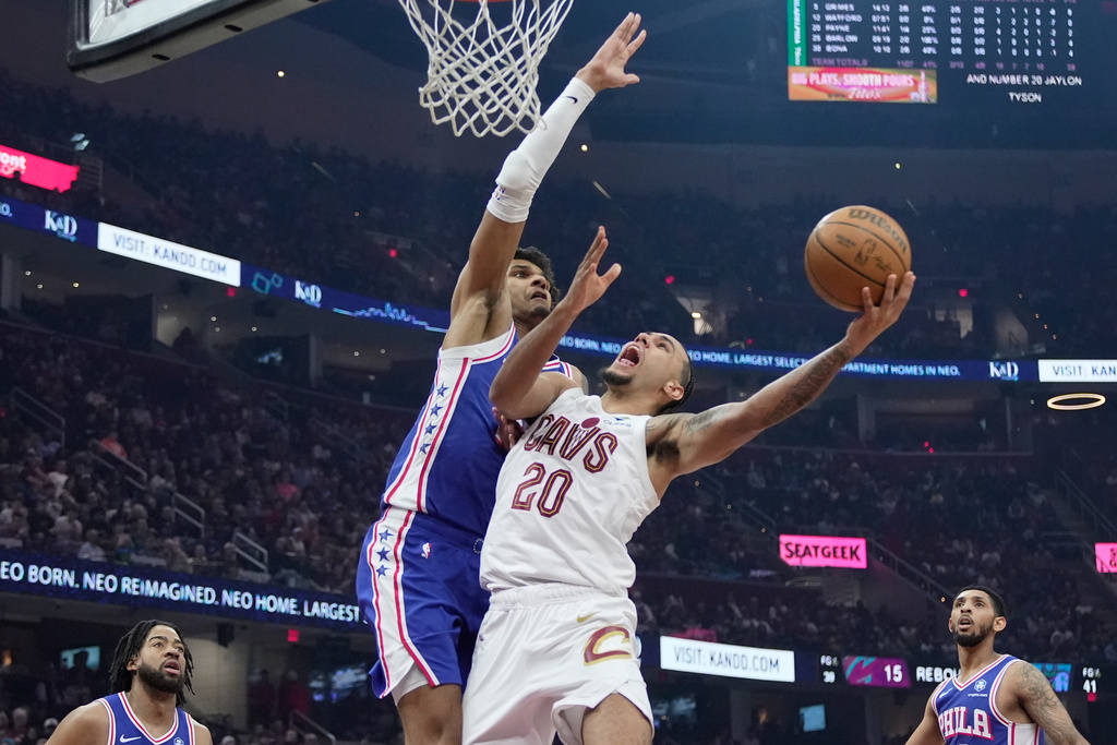 Cleveland Cavaliers guard Jaylon Tyson (20) shoots as Philadelphia 76ers forward Dominick Barlow, left, defends in the first half of an NBA basketball game in Cleveland, Monday, March 9, 2026. (AP Photo/Sue Ogrocki)