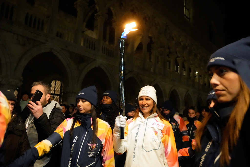 A torchbearer holds an Olympic torch flame in Venice, Italy, Thursday, Jan. 22, 2026, and its journey will conclude in Milan on February 6 for the Winter Olympics opening ceremony. (AP Photo/Luca Bruno)