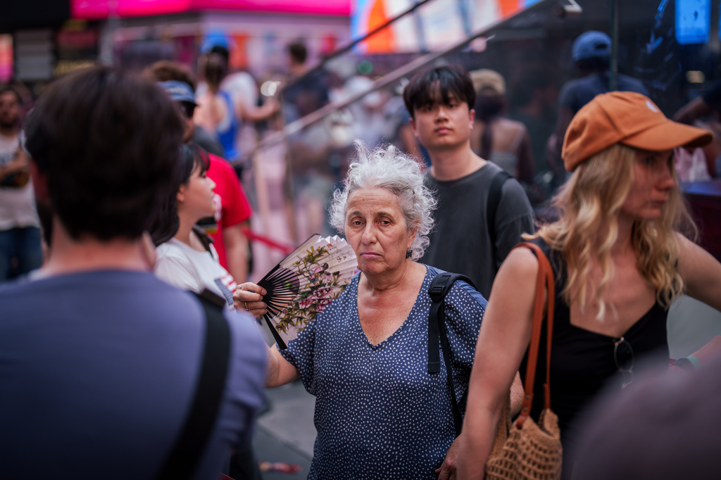 FILE - A person uses a fan as they wait in line to purchase Broadway tickets in Times Square, during a heat advisory in New York, May 19, 2026. (AP Photo/Adam Gray, File)