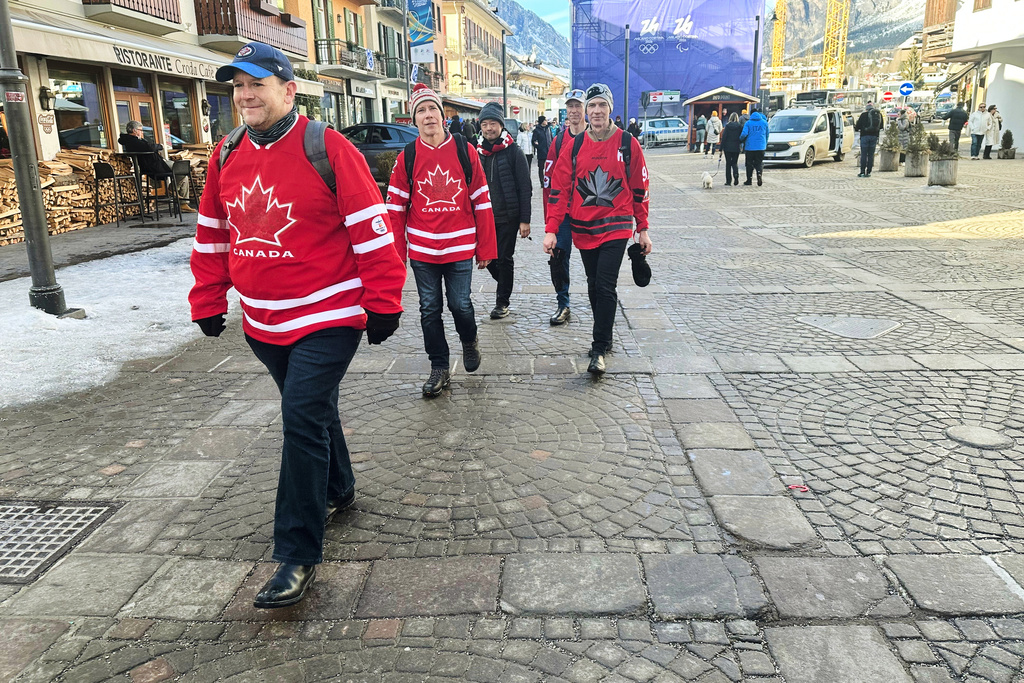 Dan Wilton, of Vancouver, Canada, left walks with his friends without jackets as temperatures rise in the host city, during the 2026 Winter Olympics in Cortina d'Ampezzo, Italy, Sunday, Feb. 8, 2026. (AP Photo/ Jennifer McDermott)