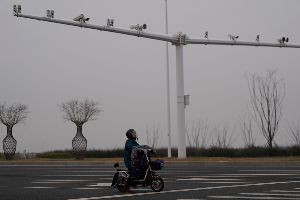 A motorist sits at an intersection near a row of surveillance cameras in Changzhou city in eastern China's Jiangsu province on Friday, Dec. 13, 2024. (AP Photo/Ng Han Guan)