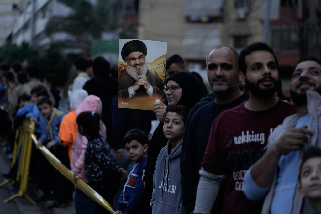 A woman holds a pictures of Hezbollah's former leader Hassan Nasrallah as people wait to welcome Pope Leo XIV upon his arrival to Beirut, Lebanon, Sunday, Nov. 30, 2025. (AP Photo/Bilal Hussein)