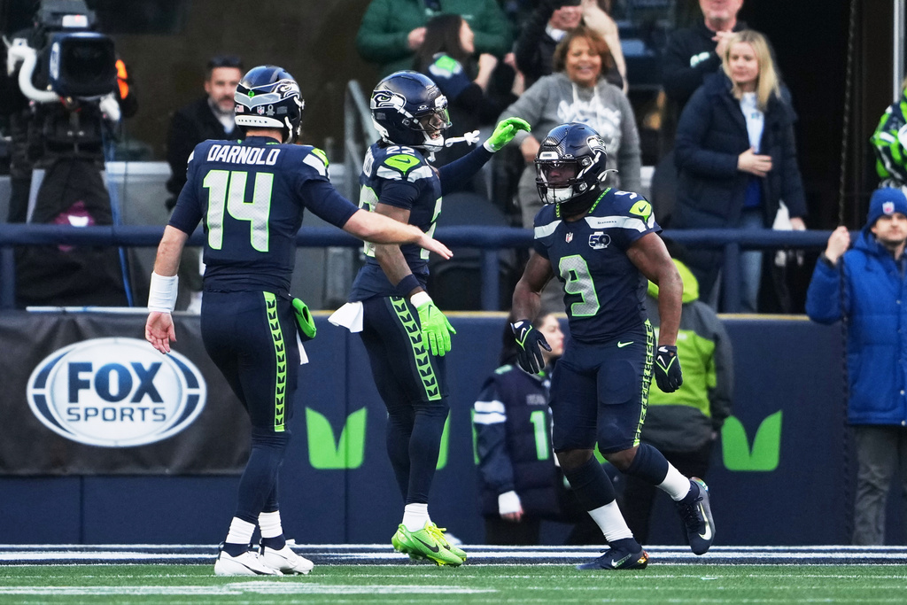 Seattle Seahawks running back Kenneth Walker III (9) celebrates his touchdown run with wide receiver Rashid Shaheed (22) and quarterback Sam Darnold (14) during the first half of the NFC Championship NFL football game against the Los Angeles Rams, Sunday, Jan. 25, 2026, in Seattle. (AP Photo/Lindsey Wasson)