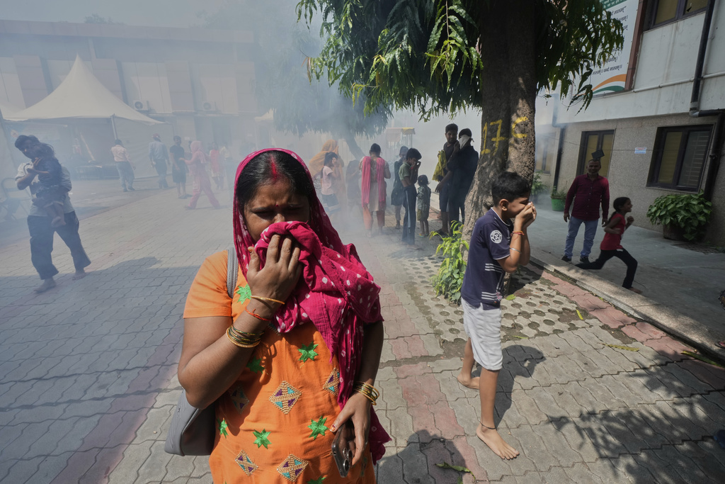 Bindu Pandey, center, cover her nose as officials fumigate in a temporary school shelter, which houses residents displaced from the banks of the Yamuna River by incessant rain in the higher regions in New Delhi, India, Friday, Sept. 5, 2025. (AP Photo/Manish Swarup)