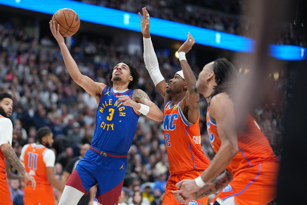 Denver Nuggets guard Julian Strawther, left, drives to the rim as Oklahoma City Thunder guard Shai Gilgeous-Alexander and forward Jaylin Williams, right, defend in the first half of an NBA basketball game, Sunday, Feb. 1, 2026, in Denver. (AP Photo/David Zalubowski)
