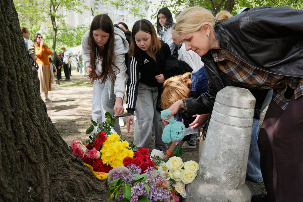 People lay flowers in front of a house heavily damaged after a Russian strike on residential neighbourhood in Kyiv, Ukraine, Friday, May 15, 2026. (AP Photo/Efrem Lukatsky)