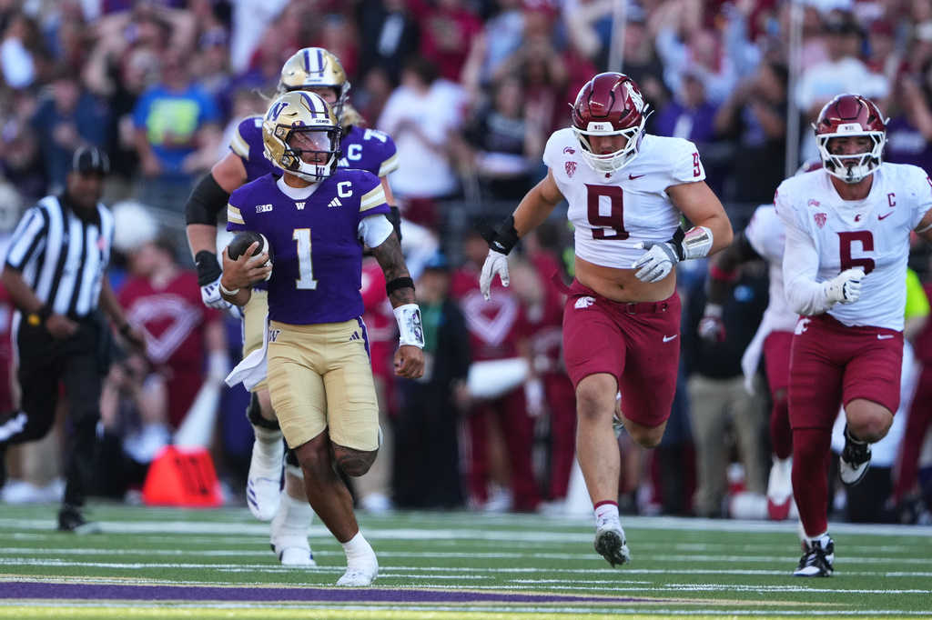 Washington quarterback Demond Williams Jr. (1) rushes against Washington State, including defensive end Matyus McLain (9) during the second half of an NCAA college football game, Sunday, Sept. 6, 2026, in Seattle. (AP Photo/Lindsey Wasson)