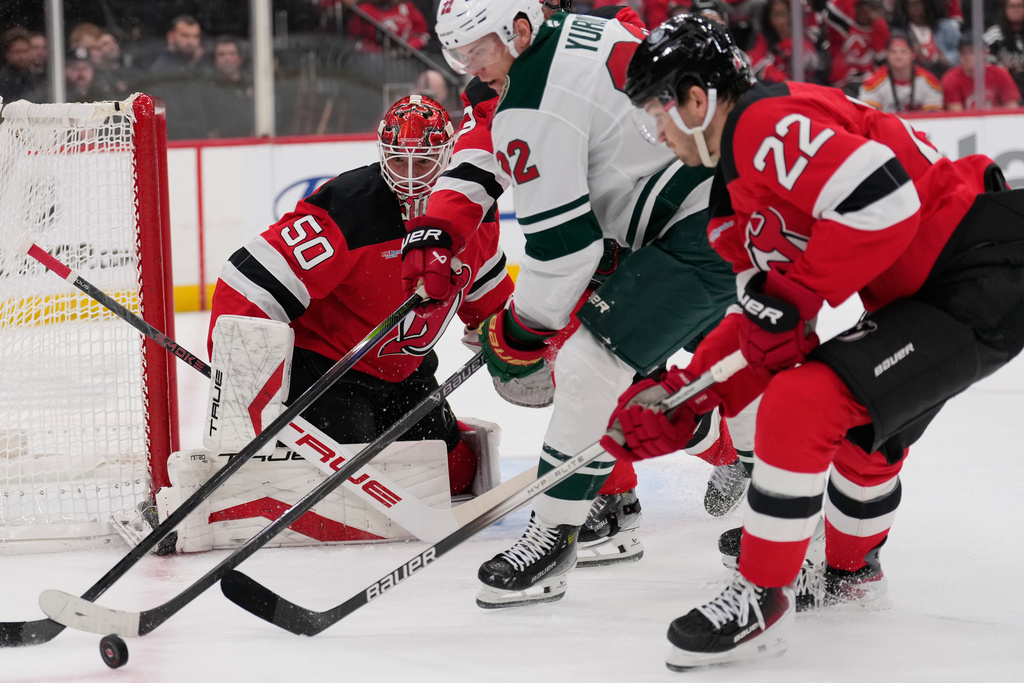 New Jersey Devils goaltender Nico Daws, left, defends the goal during the first period of an NHL hockey game against the Minnesota Wild Wednesday, Oct. 22, 2025, in Newark, N.J. (AP Photo/Seth Wenig)