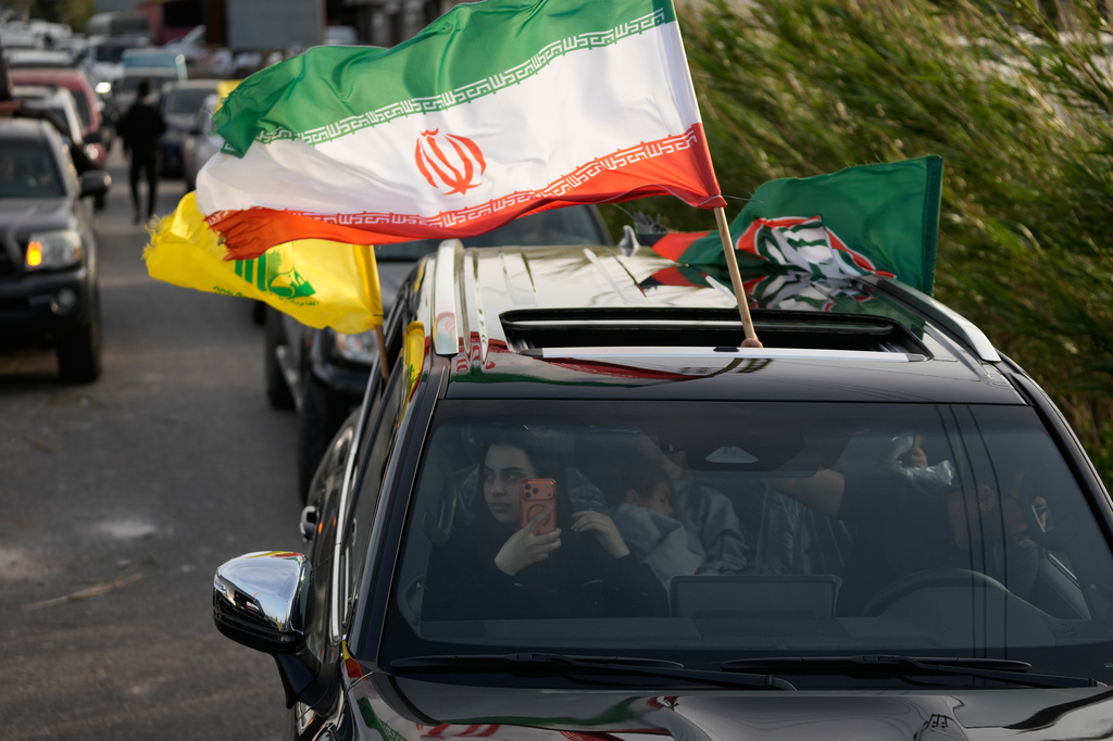 A displaced man waves the Iranian flag, as he returns with his family to their village following a ceasefire between Hezbollah and Israel, in Qasmiyeh near Tyre city, south Lebanon, Friday, April 17, 2026. (AP Photo/Mohammed Zaatari)