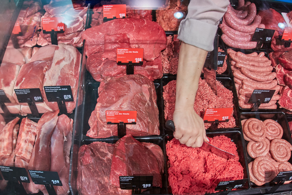 A woman works at the meat counter of a super market in Wehrheim near Frankfurt, Germany, Tuesday, March 31, 2026. (AP Photo/Michael Probst)