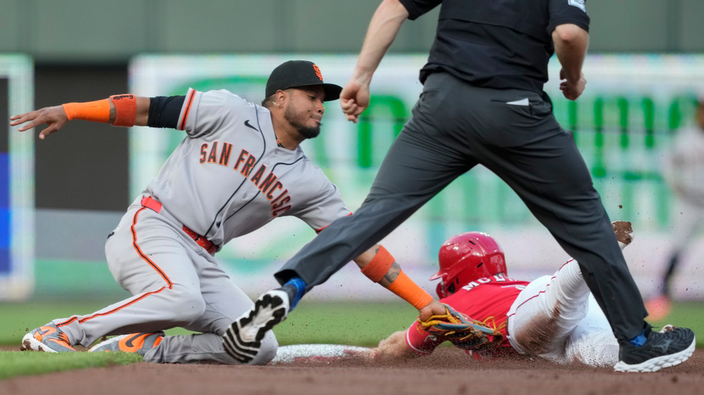 Cincinnati Reds' Matt McLain, right, is caught stealing second base by San Francisco Giants shortstop Willy Adames, left, as umpire Junior Valentine moves in during the first inning of a baseball game in Cincinnati, Tuesday, April 14, 2026. (AP Photo/Carolyn Kaster)