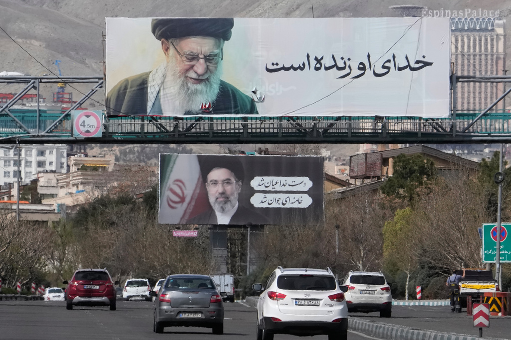 Vehicles drive under billboards showing portraits of the late Iranian Supreme Leader Ayatollah Ali Khamenei, foreground, and his son Ayatollah Mojtaba Khamenei, the successor to him, along a highway in Tehran, Iran, Tuesday, March 24, 2026. (AP Photo/Vahid Salemi)