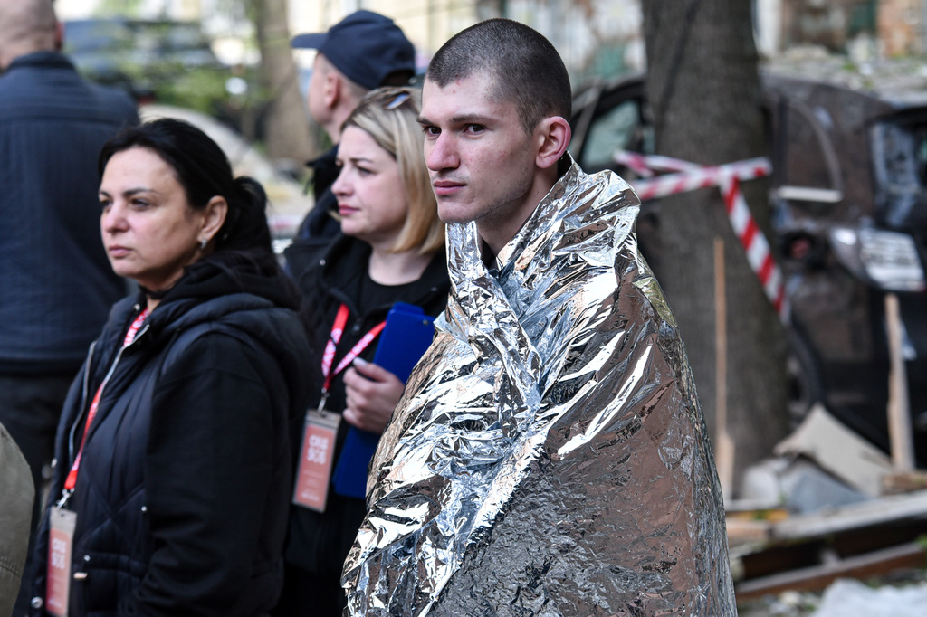 A man covered in thermal blanket stands in a yard of a residential building damaged by a Russian strike on Dnipro, Ukraine, Saturday, April 25, 2026. (AP Photo/Mykola Synelnykov)