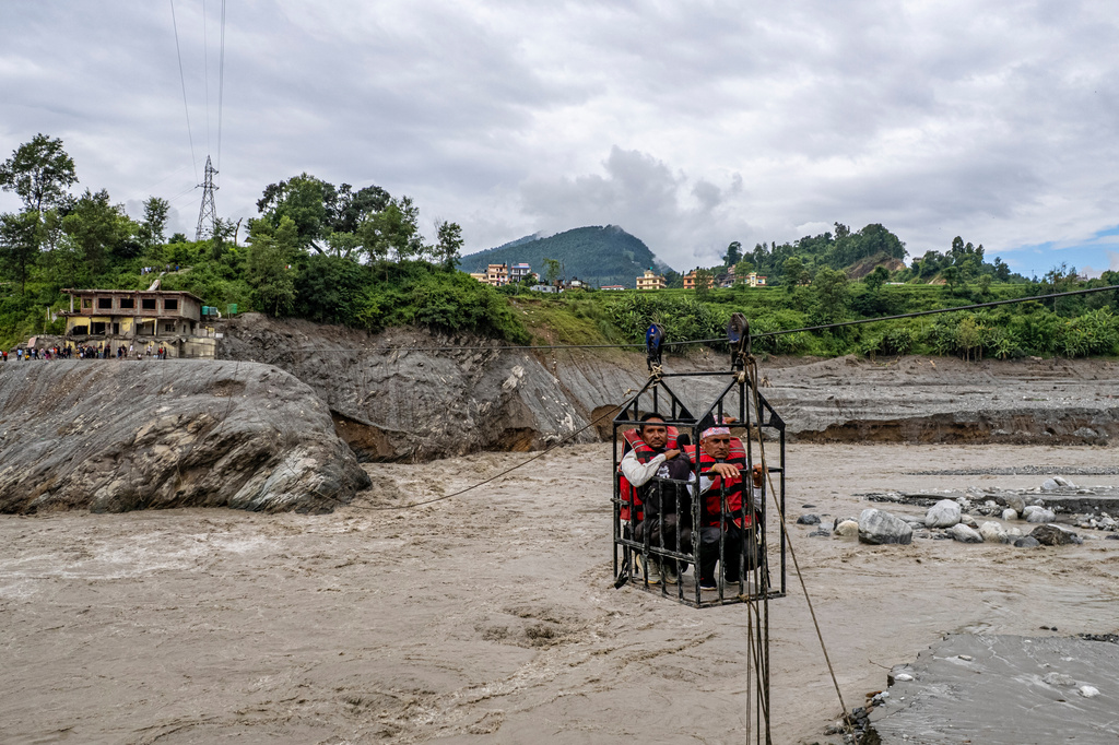 Residents commute across the Trishuli river on a newly installed zipline in the aftermath of flash floods at Bidur in Nepal's Nuwakot district, Thursday, Sept. 3, 2026. (AP Photo/Rajesh Kumar Singh)