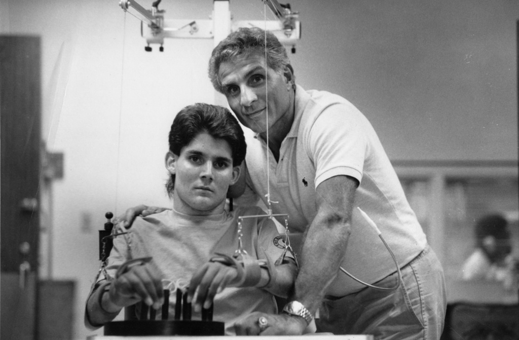 In this photo released by the University of Miami, President Marc Buoniconti and his father, NFL Hall of Famer Nick Buoniconti, poses with Marc in rehab in Miami in 1986. (The Miami Project/University of Miami via AP)