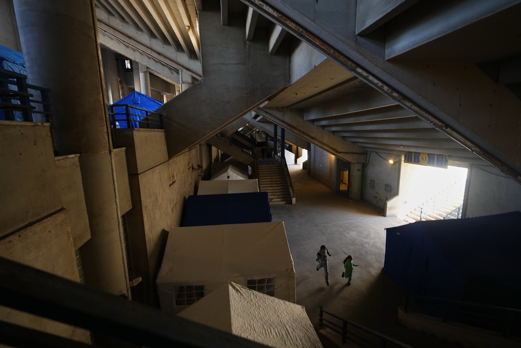 Displaced children run between tents set up inside the Camille Chamoun Sports City Stadium, which has been turned into a shelter for people displaced by Israeli airstrikes in southern Lebanon and Dahiyeh, Beirut's southern suburbs, in Beirut, Lebanon, Tuesday, March 10, 2026. (AP Photo/Hassan Ammar)