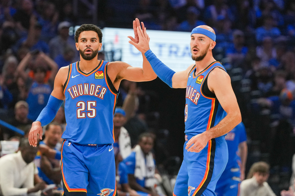 Oklahoma City Thunder guards Ajay Mitchell, left, and Alex Caruso, right, celebrate during the first half of an NBA basketball game against the New Orleans Pelicans, Sunday, Nov. 2, 2025, in Oklahoma City. (AP Photo/Kyle Phillips)