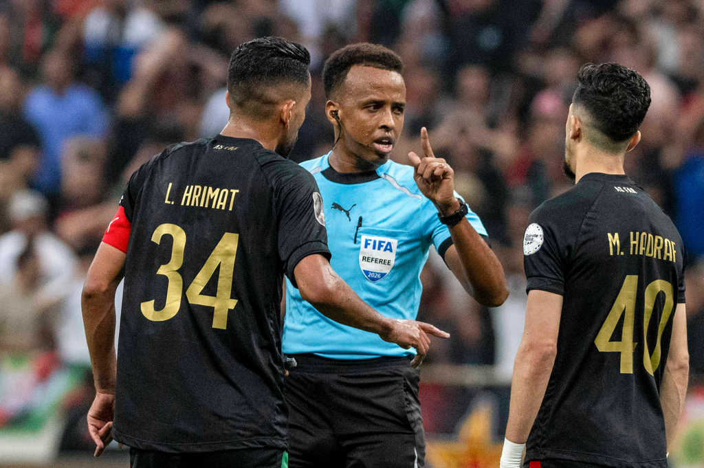 Referee Omar Artan, center, of Somalia, is confronted by players after calling a penalty kick during the CAF Champions League final soccer match between AS FAR Rabat and Mamelodi Sundowns, in Rabat, Morocco, Sunday, May 24, 2026. (AP Photo/Mosa'ab Elshamy)