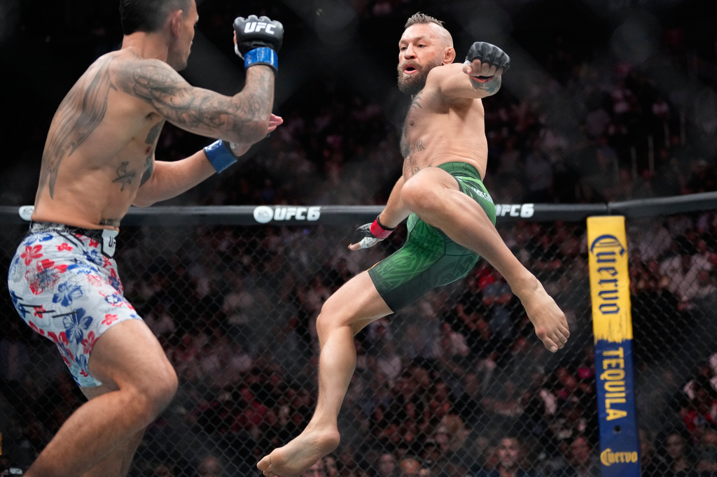 Conor McGregor, right, jumps into the air for a kick as he fights Max Holloway in a welterweight fight at the UFC 329 mixed martial arts event Saturday, July 11, 2026, in Las Vegas. (AP Photo/John Locher)