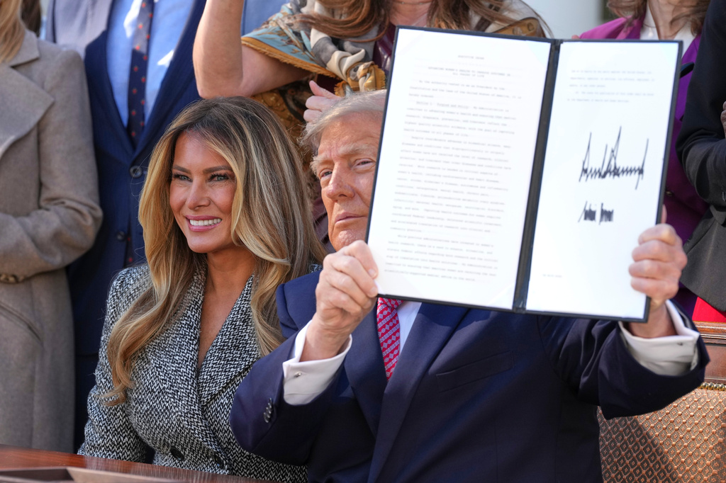 President Donald Trump holds up a signed executive order alongside first lady Melania Trump at an event about women's health, in the Rose Garden of the White House, Monday, Oct. 19, 2026, in Washington. (AP Photo/Alex Brandon)