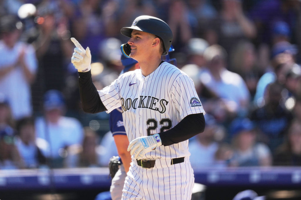 Colorado Rockies' Mickey Moniak, front, gestures as he crosses home plate after hitting a two-run home run off Los Angeles Dodgers relief pitcher Blake Treinen in the seventh inning of a baseball game Sunday, April 19, 2026, in Denver. (AP Photo/David Zalubowski)