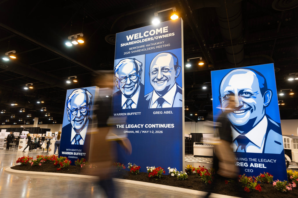 People walk past large portraits of Berkshire Hathaway's Warren Buffett, left, and CEO Greg Abel inside the Berkshire Hathaway annual meeting on Saturday, May 2, 2026, in Omaha, Neb. (AP Photo/Rebecca S. Gratz)