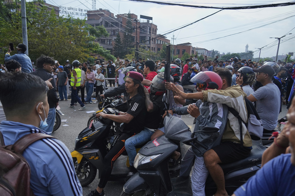 A protester rides on two wheelers carrying a firearm with others during a protest against a social media ban and corruption in Kathmandu, Nepal, Tuesday, Sept. 9, 2025. (AP Photo/Niranjan Shrestha)