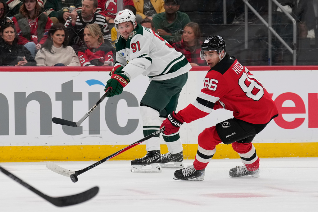 Minnesota Wild's Vladimir Tarasenko, left, passes past New Jersey Devils' Jack Hughes during the first period of an NHL hockey game Wednesday, Oct. 22, 2025, in Newark, N.J. (AP Photo/Seth Wenig)