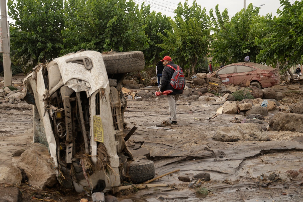A man walks amid the destruction after heavy rain triggered flooding in Arequipa, Peru, Monday, Feb. 23, 2026. (AP Photo/Jose Sotomayor)