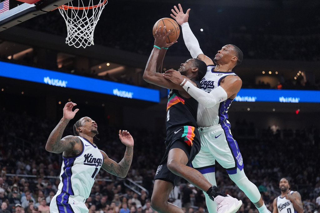 San Antonio Spurs guard De'aaron Fox (4) is blocked by Sacramento Kings guard Russell Westbrook (18) as he drives to the basket during the second half of an NBA basketball game in Austin, Texas, Saturday, Feb. 21, 2026. (AP Photo/Eric Gay)