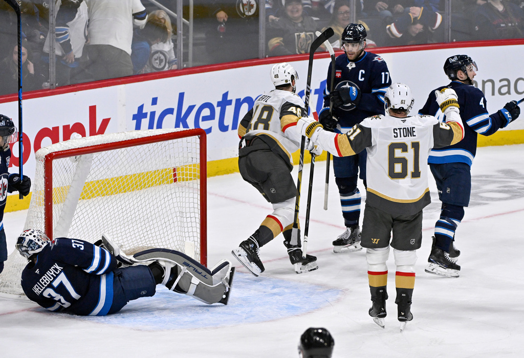 Vegas Golden Knights' Tomas Hertl (48) celebrates his game-winning goal in overtime against Winnipeg Jets goaltender Connor Hellebuyck (37) with Mark Stone (61) during their NHL hockey game in Winnipeg, Tuesday Jan. 6, 2026. (Fred Greenslade/The Canadian Press via AP)