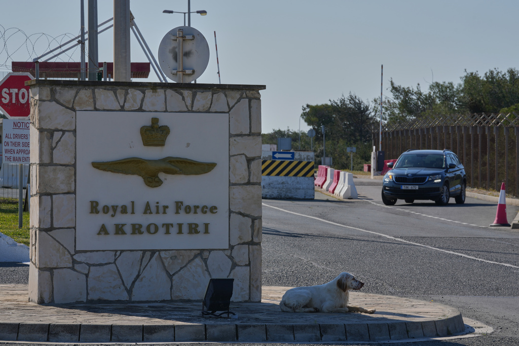 A dog sits at the main gate of the U.K.’s RAF Akrotiri air base after it was hit by a drone strike early morning near Limassol, Cyprus, Monday, March, 2, 2026. (AP Photo/Petros Karadjias)