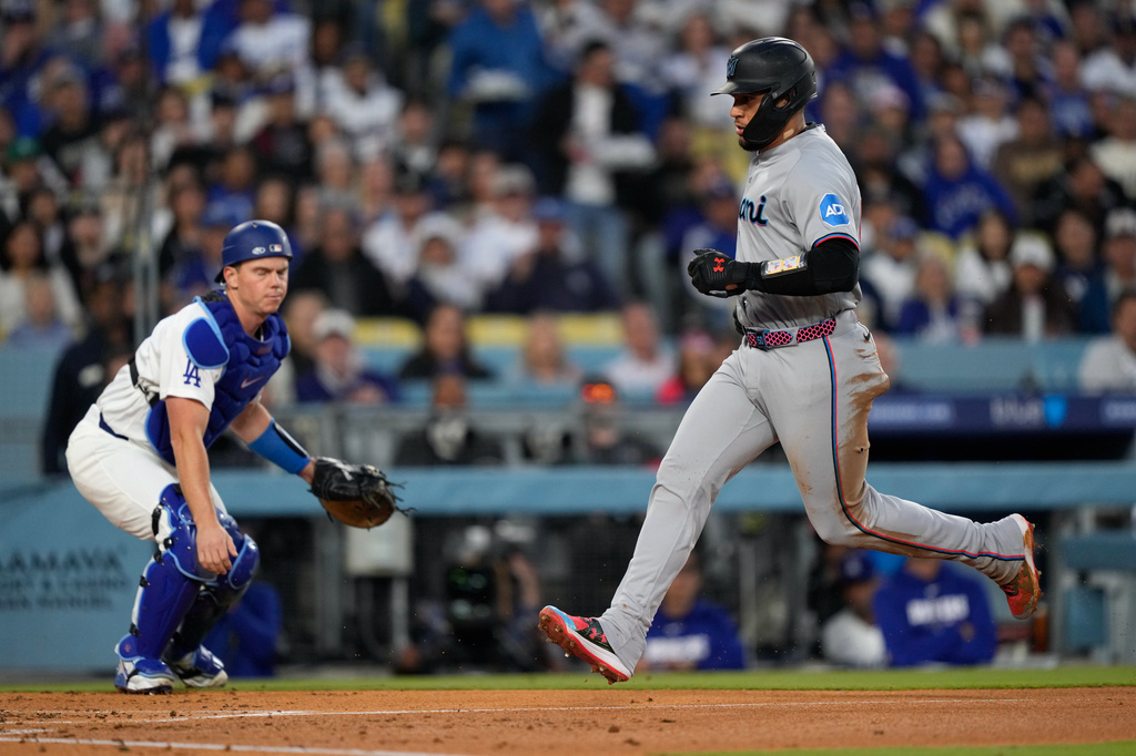 Miami Marlins' Agustin Ramirez, right, scores on a sacrifice fly by Owen Caissie as Los Angeles Dodgers catcher Will Smith watches during the second inning of a baseball game Tuesday, April 28, 2026, in Los Angeles. (AP Photo/Mark J. Terrill)