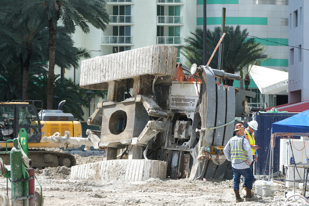 Workers stand near the site where a large construction crane collapsed, Monday, Sept. 14, 2026, in Miami. (AP Photo/Marta Lavandier)