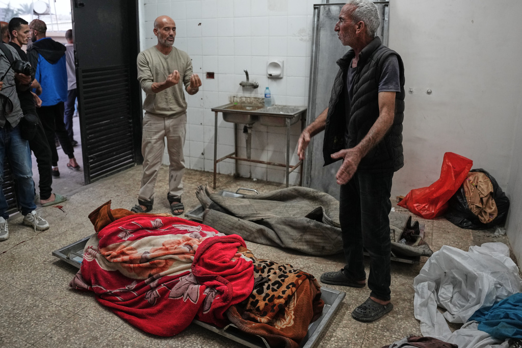 Palestinians check the bodies of people killed in Israeli strikes on the Gaza Strip at the morgue of Al-Aqsa Hospital in Deir al-Balah, Saturday, Nov. 22, 2025. (AP Photo/Abdel Kareem Hana)