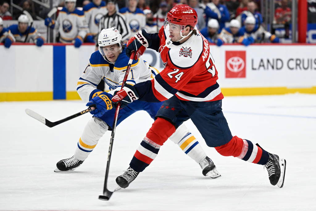 Washington Capitals left wing Connor McMichael (24) shoots the puck past Buffalo Sabres center Ryan McLeod during the first period of an NHL Hockey game, Saturday, April 4, 2026, in Washington. (AP Photo/John McDonnell)