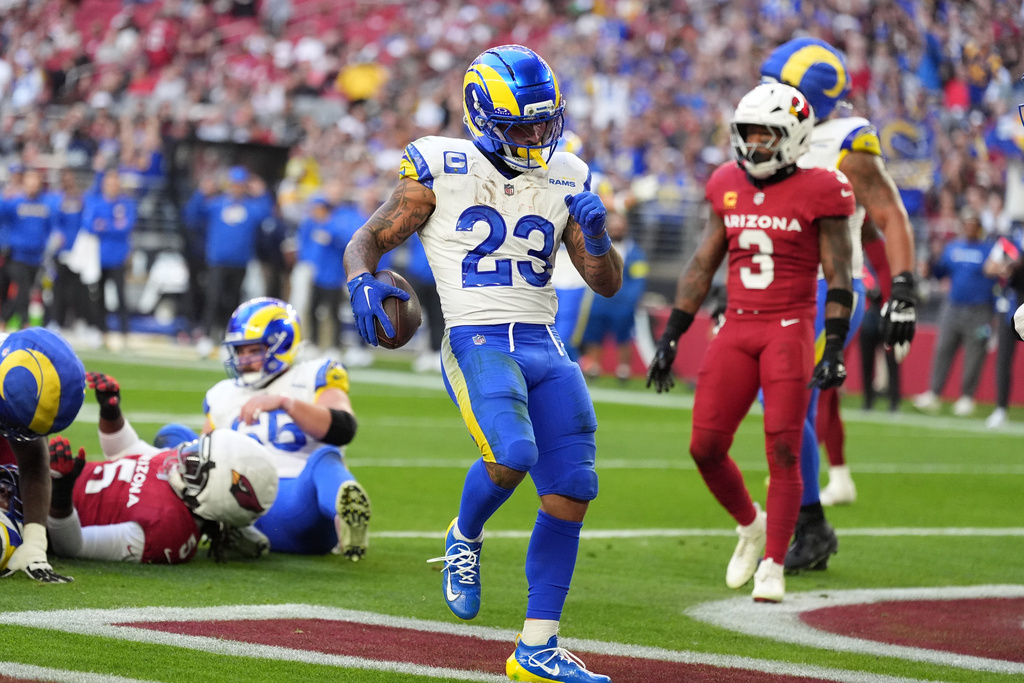 Los Angeles Rams running back Kyren Williams celebrates after running for a touchdown as Arizona Cardinals safety Budda Baker looks on in the first half of an NFL football game, Sunday, Dec. 7, 2025, in Glendale, Ariz. (AP Photo/Ross D. Franklin)