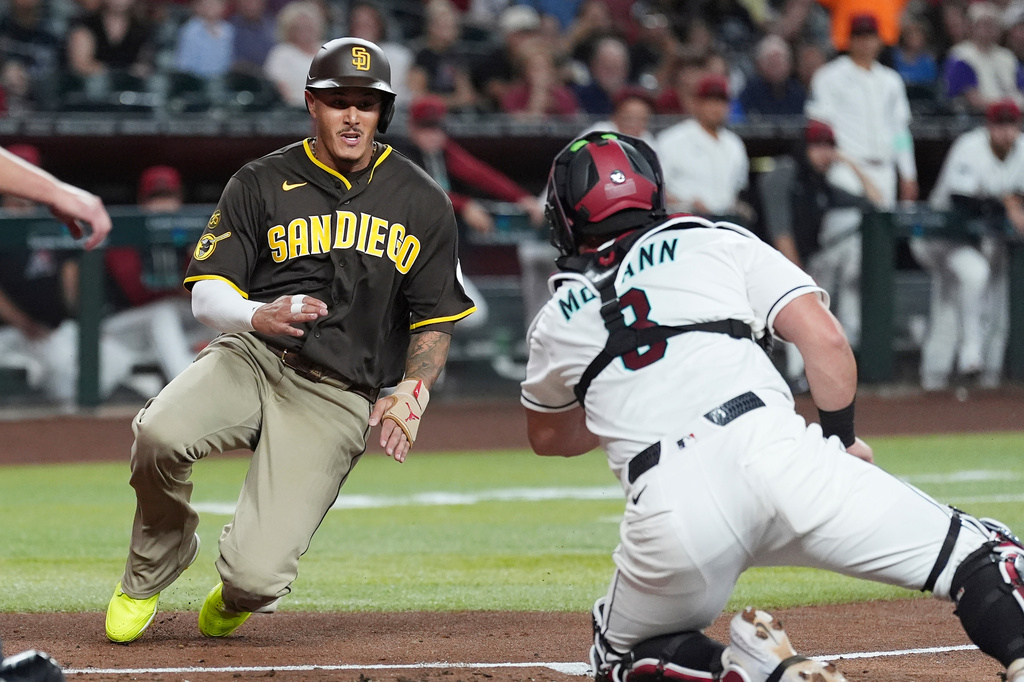 San Diego Padres' Manny Machado, left, scores a run as Arizona Diamondbacks catcher James McCann, right, loses the baseball during the first inning of a baseball game, Tuesday, Aug. 4, 2026, in Phoenix. (AP Photo/Ross D. Franklin)