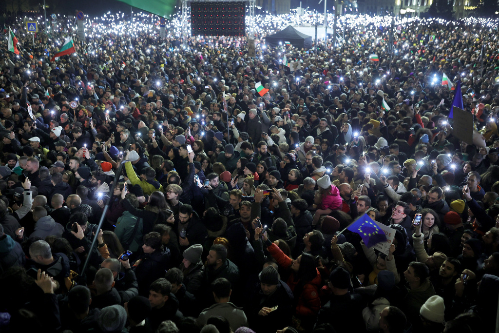 Protesters light their phone's as torches as a swelling crowd of tens of thousands of Bulgarians filled Sofia's central square, demanding the government's resignation amid rising anger over corruption and contested economic policies, Sofia, Bulgaria, Wednesday, Dec. 10, 2025. (AP Photo/Valentina Petrova)